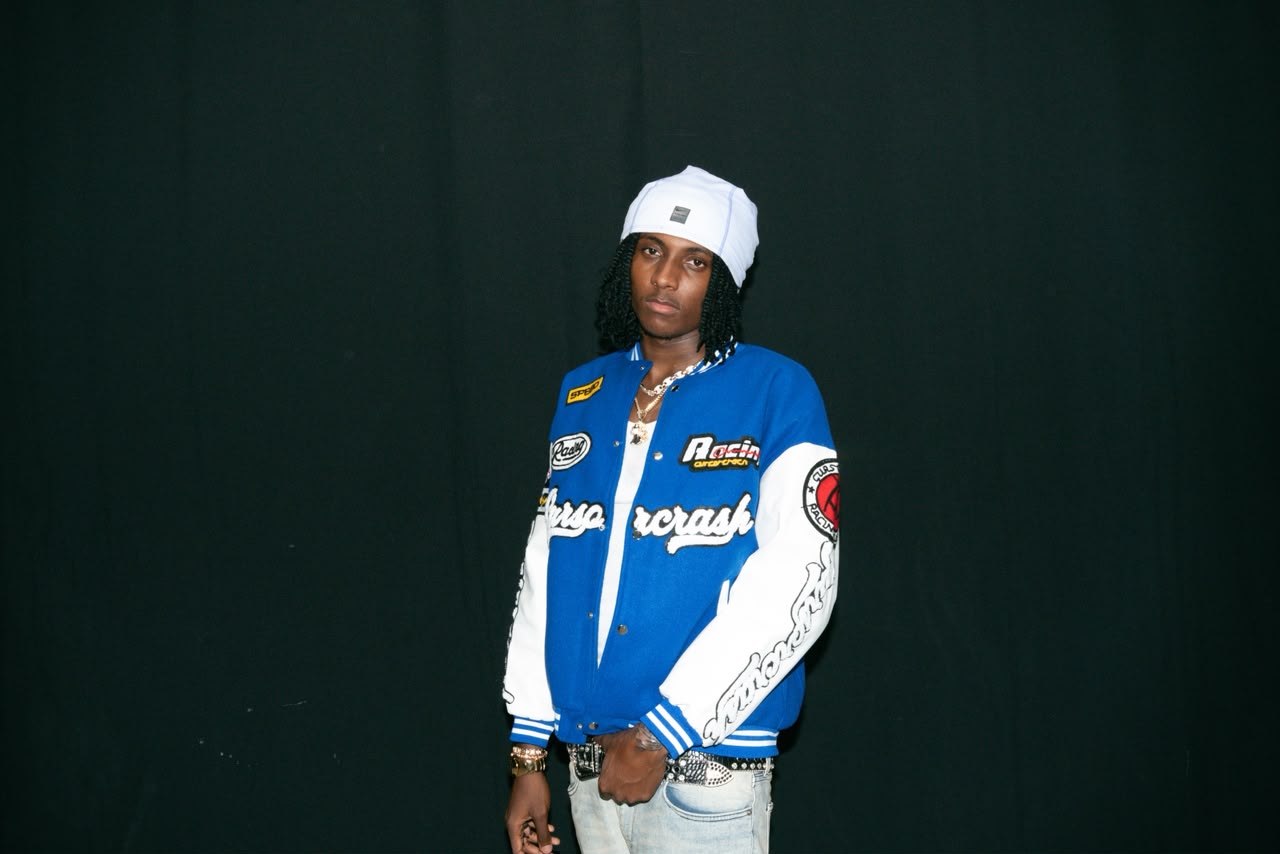 Koddy G con chaqueta azul frente a un fondo oscuro